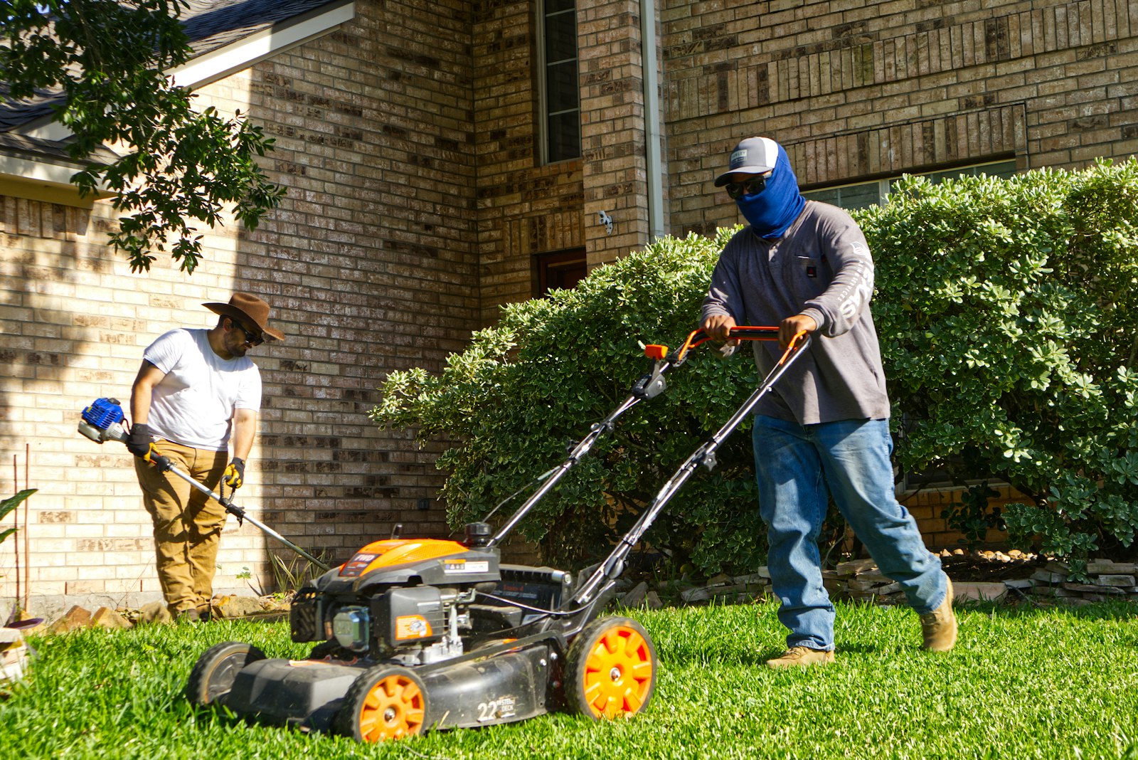 Two-person crew mowing and trimming a residential front lawn